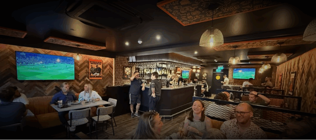 Interior of Ginger Wings bar showing installed audio and screen setup in use by guests